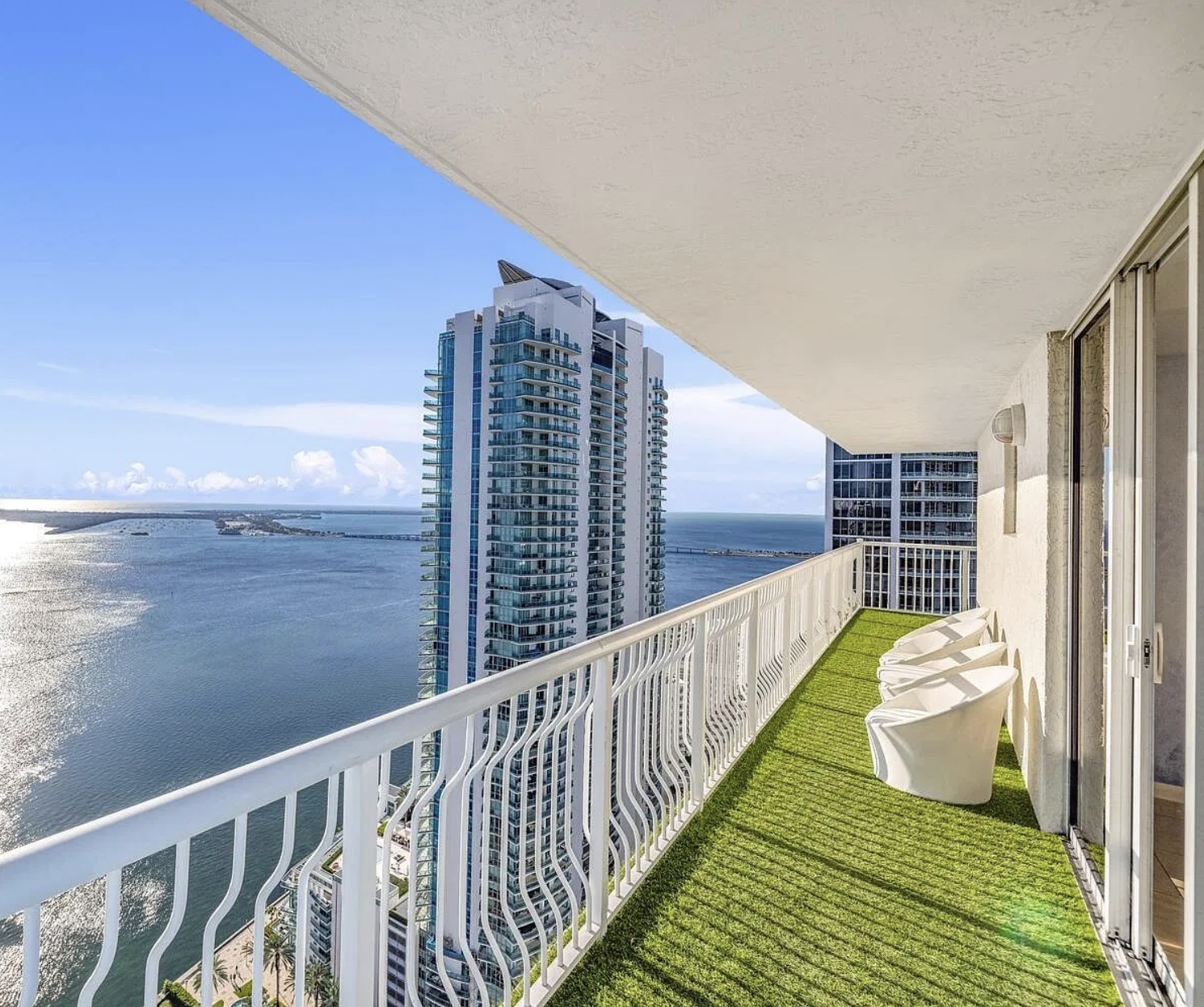 High-rise balcony with white lounge chairs and sweeping bay views
